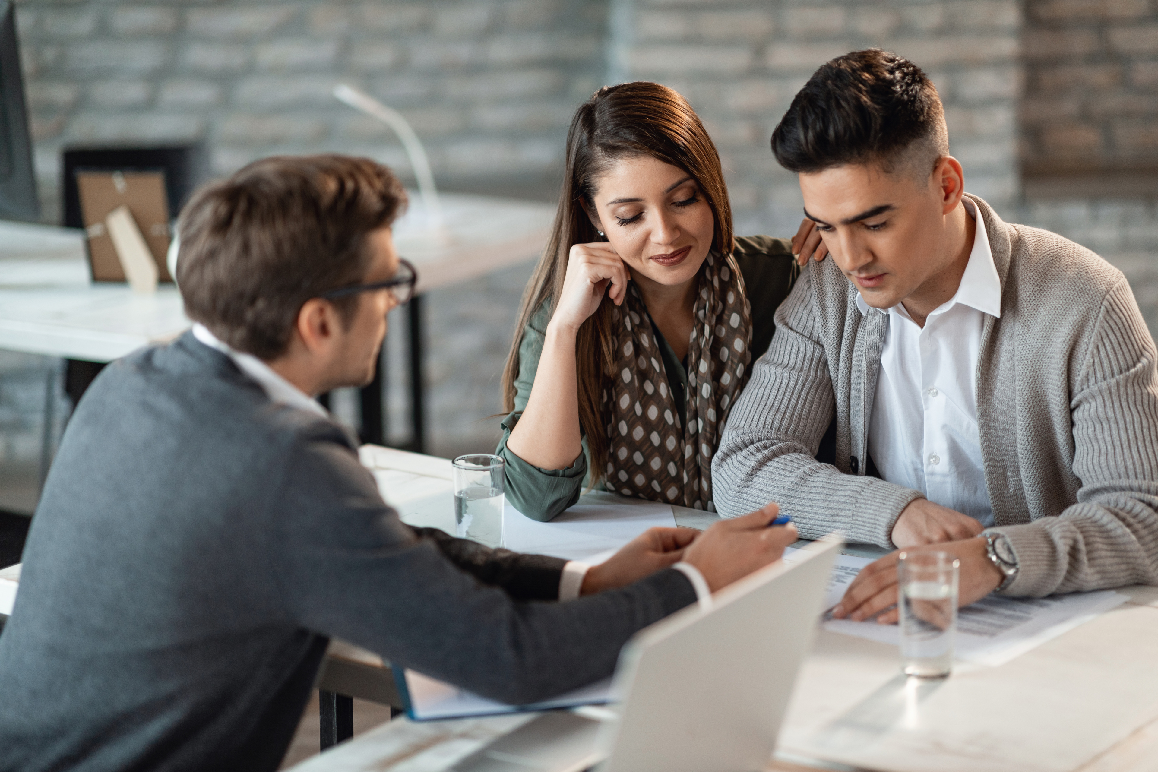 Young Couple And Insurance Agent Going Through Paperwork On A Meeting.